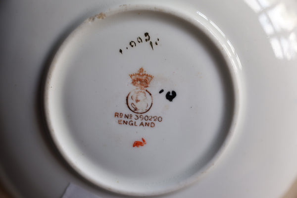 Close-up of the bottom of a white porcelain plate or cup, showing a printed Royal Warrant emblem with a crown and the text 'RENS 350290 ENGLAND'.