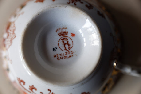 Close-up of the inside bottom of a white porcelain teacup or teapot, showing a red printed monogram logo with a crown and the text 'RB N°3395 ENGLAND'.