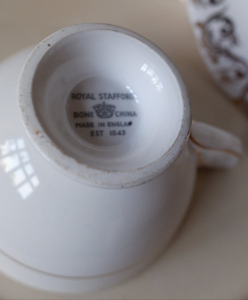 Close-up of the inside base of a white ceramic teacup or small bowl, showing printed text that reads 'ROYAL STAFFORD BONE CHINA MADE IN ENGLAND EST 1845' with a crown logo.