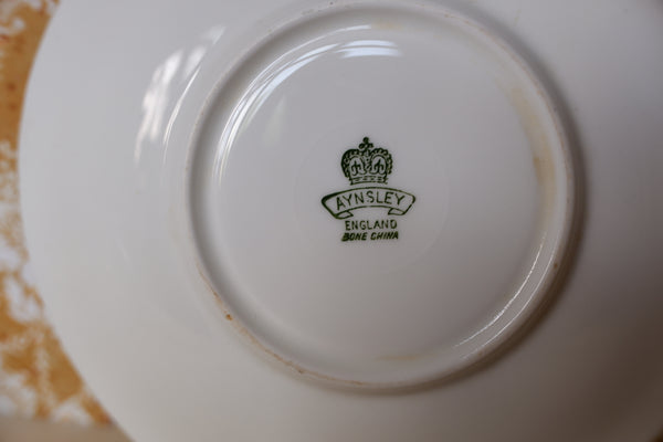 Close-up of the bottom of a white ceramic plate or teacup, showing the green printed Aymsley England Dore China mark in the center.
