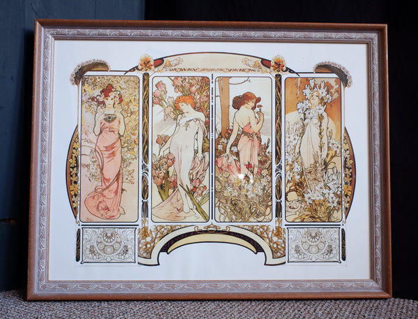 A framed Art Nouveau style print featuring four vertical panels with elegant women in flowing pink and white garments surrounded by floral and botanical motifs, set in a brown wooden frame with a white mat.